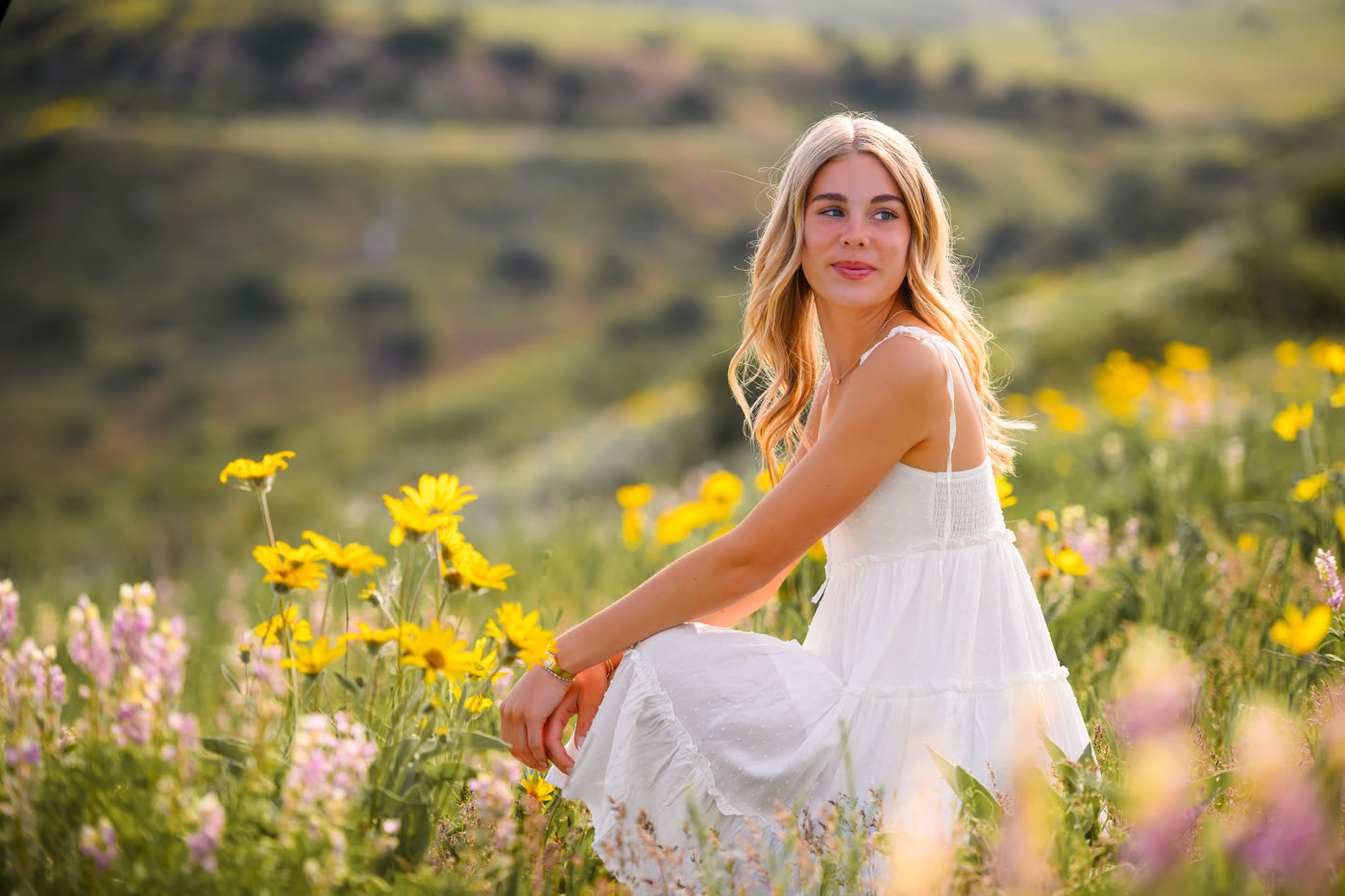 Senior portrait, blonde graduate in wildflower field at golden hour